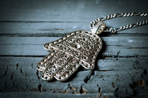 closeup of an old hamsa amulet, also known of the hand of fatima or the hand of mary, on a gray rustic wooden surface