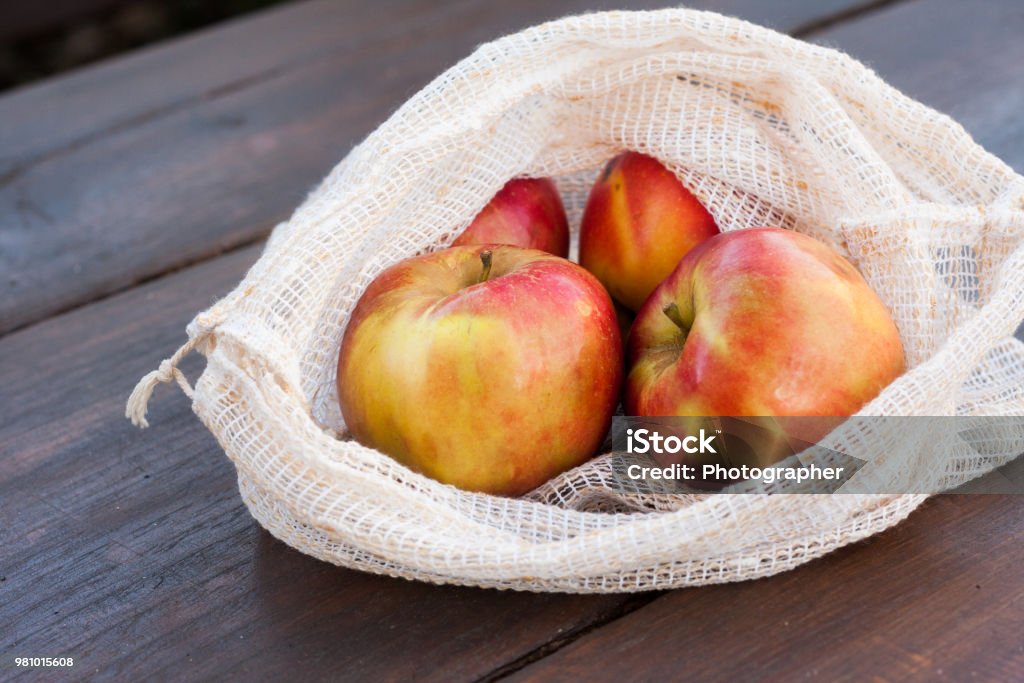 Reusable, environmentally friendly pretty produce shopping bags Zero waste, plastic free recycled textile produce bag for carrying fruit (apple, orange, pear and a banana) or vegetables, a wooden surface. Bags are made with a sewing machine out of old curtains. Bag Stock Photo