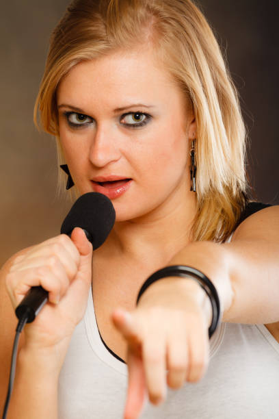 istock Blonde woman singing to microphone 981040160