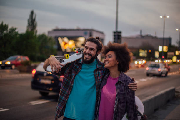 istock Happy man holding skateboard and hugging his girlfriend 981047034