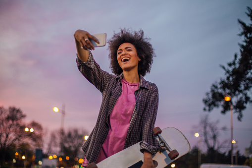 Silly woman with skateboard making a face while taking selfie