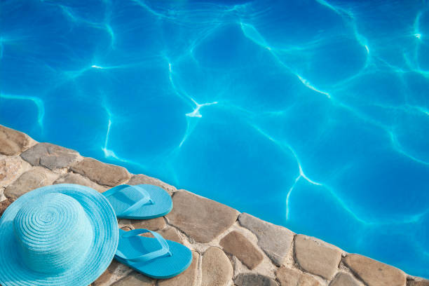 istock Blue hat and flip flop by a swimming pool 981049964
