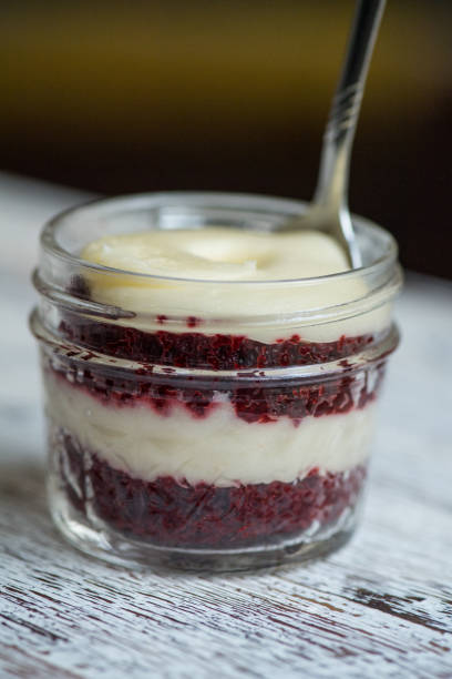 Red velvet cupcake in a glass mason jar with spoon on a table