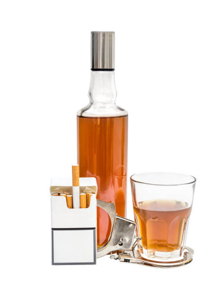 istock Pack of cigarettes with with alcohol drink and handcuffs on white. 981061624