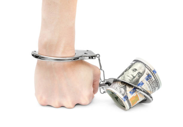 istock Hand chained to money by handcuffs. Isolated on white. 981064992
