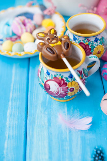 istock Easter sweets for the holiday. Spring. Bright colors on coffee mugs. Chocolate bunny. View from above. Vertical photo. 981072796