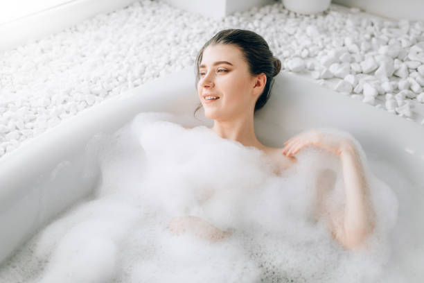 istock Attractive lady lying in bath with foam, top view 981079682