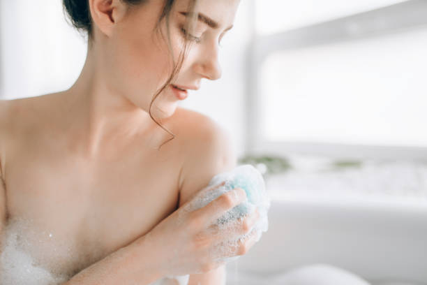 istock Female person soaps the body with a sponge 981079808
