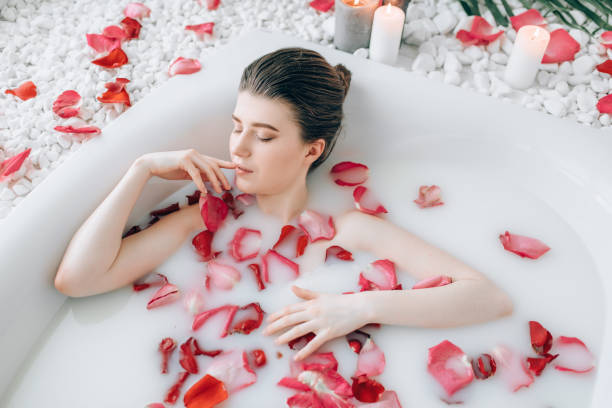 istock Attractive lady lying in bath with rose petals 981079980