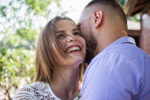 hombre joven susurrando a la mujer o novia, secreto sorprendente que dice del novio a su chica, el hombre dice palabras bonitas a su novia, la chica está sonriendo o riendo - whispering couple discussion smiling fotografías e imágenes de stock