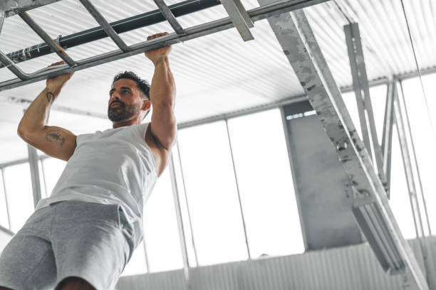 Athletic Man Exercising in an Abandoned Warehouse An athletic mature man is doing chin-up exercises inside an abandoned warehouse. chin ups photos stock pictures, royalty-free photos & images