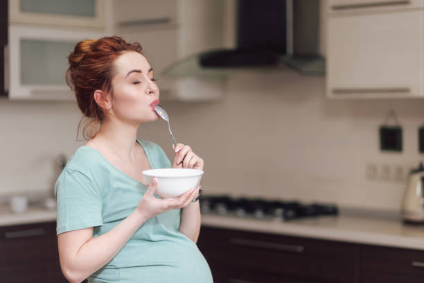 Beautiful pregnant woman eating cereals stock photo