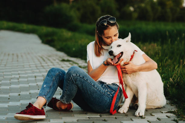 istock Female kissing white dog sitting on pathway 981097902