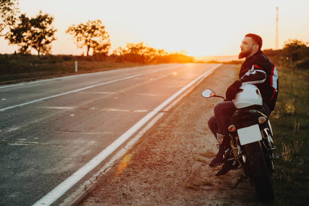 istock Man resting sitting on motorbike at roadside 981097906