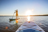 Full Length Of Man On Paddle Board In Sea During Sunset