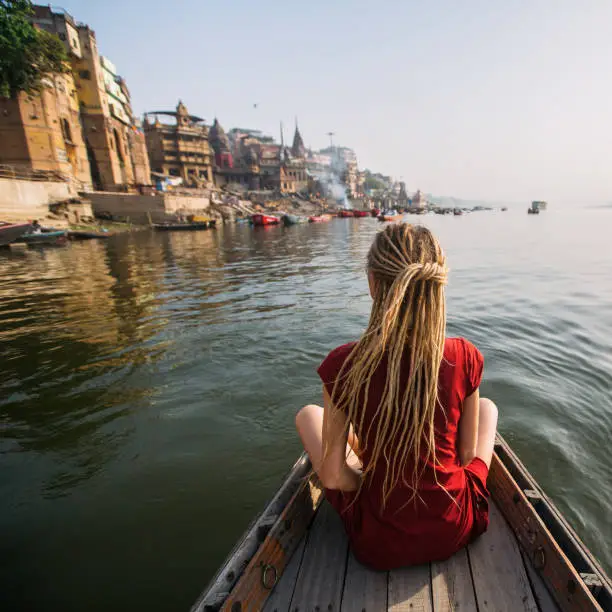 Photo of Woman traveler on a boat in the Ganges river waters, Varanasi, India.