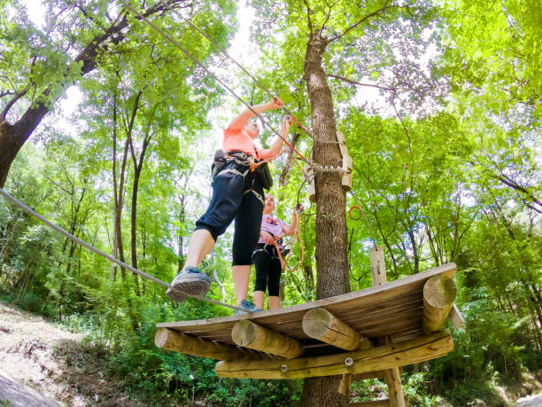 istock Assistant Looking Over a Young Girl Enjoying in Fun Park in Forest 981108592