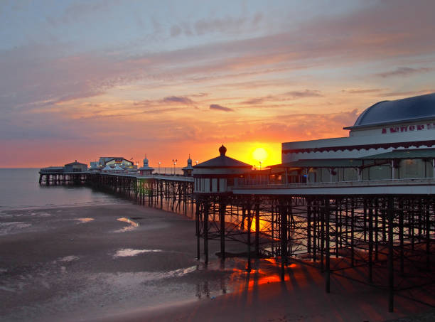 la puesta de sol en el muelle norte en blackpool con brillante luz reflejada en la playa y el cielo de colorido crepuscular - north pier fotografías e imágenes de stock