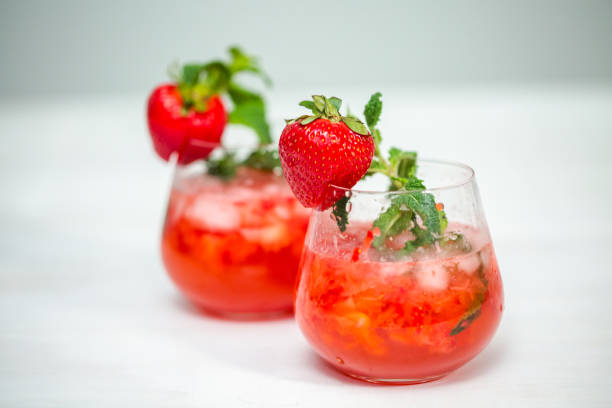 Infused water with fresh strawberries, lime, lemon and basil served in a glass.