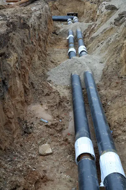 Black steel pipes of the water pipeline in the excavated earth ditch