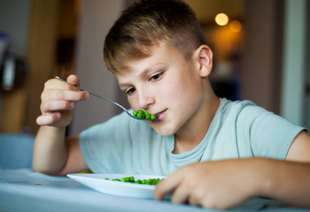 istock Boy Eating Green Peas 981137428