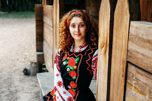 Middle age woman with traditional bulgarian clothes enjoys the aroma of oil-bearing rose (Rosa Damascena). Rose harvesting, essential oil production