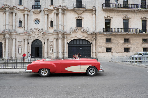 Havana, Cuba -26 April 2018: Side view of a 1950s Chevrolet Bel Air parked in front of an old building in Old Town. Two men chatting and one man looking at them in the background.