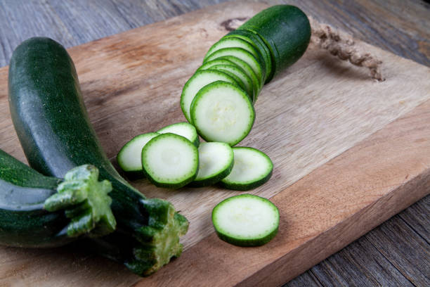 istock Two Courgettes on a wooden chopping board and another sliced courgette 981159974