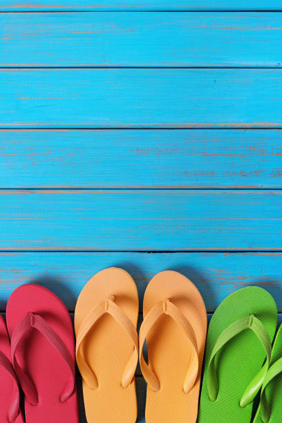 istock Flip flops in a row old weathered blue beach wood background vertical 981173200