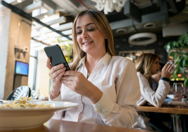 istock Woman at a restaurant texting on her cell phone 981235894