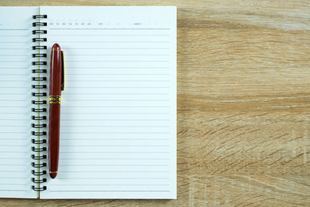 istock Fountain pen or ink pen with notebook paper on wooden working table with copy space, office desk concept. top view. 981242932