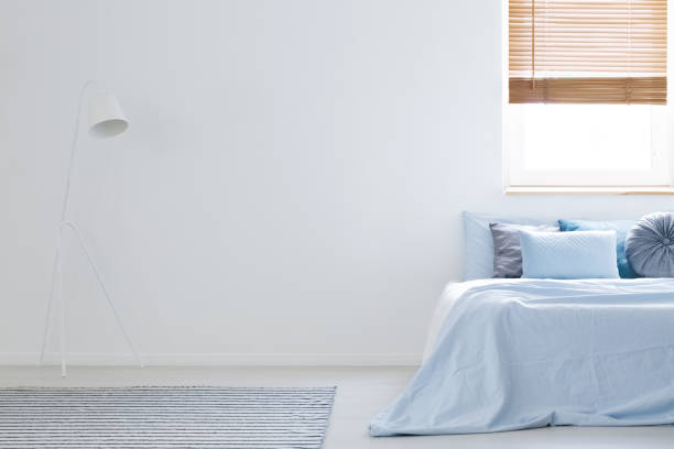 istock White lamp in bedroom interior with blue sheets on bed next to copy space. Real photo 981243274