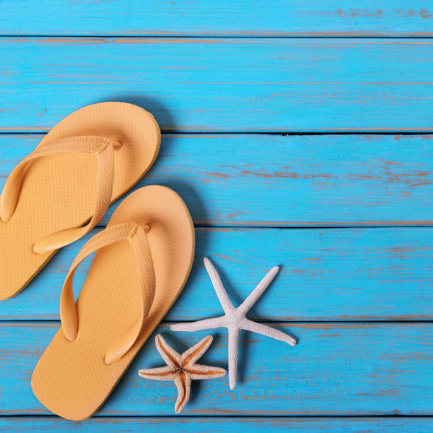 istock Flip flops starfish old distressed bright blue beach wood square 981258814