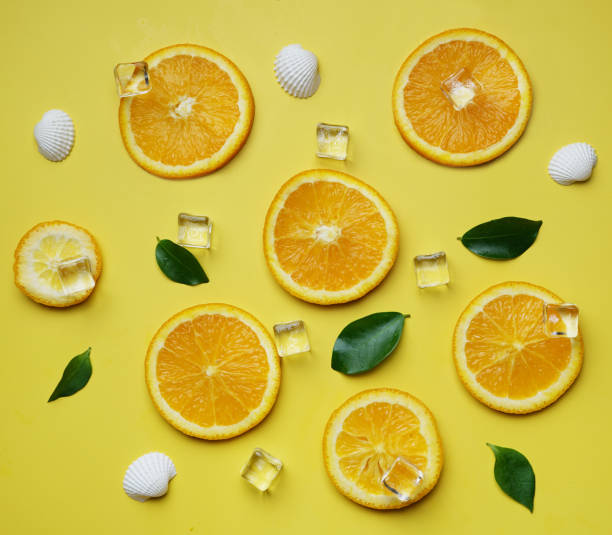 istock Orange Leaves Cube Ice Sea Shells Citrus Pattern on Yellow Background Minimal Flat Lay 981273334