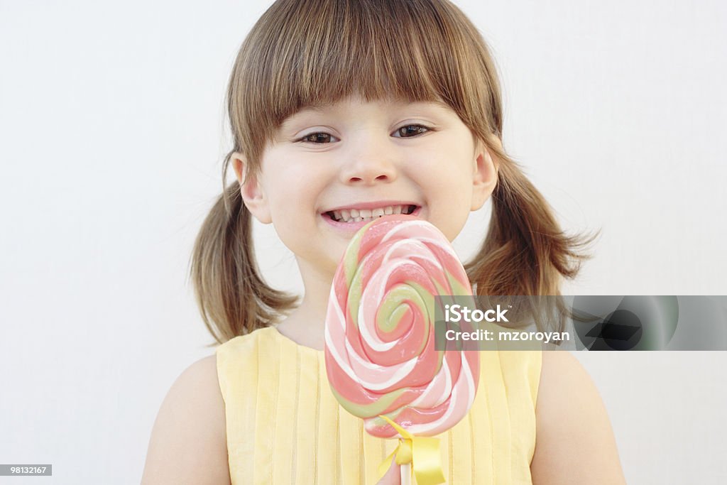 Young girl with swirled pink lolly pop Beautiful little girl holding a big round swirl lollipop Beautiful People Stock Photo