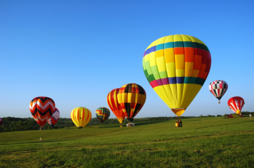 Hot air balloons landing in a field during a festival in Iowa.