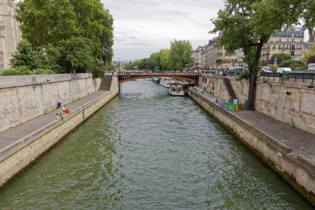 Paris - July 31, 2017: Locals relax on the banks of the River Seine, as seen from Petit Pont.