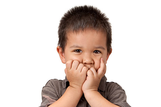 Preschool aged boy with his hand/fists over mouth  speak no evil stock pictures, royalty-free photos & images