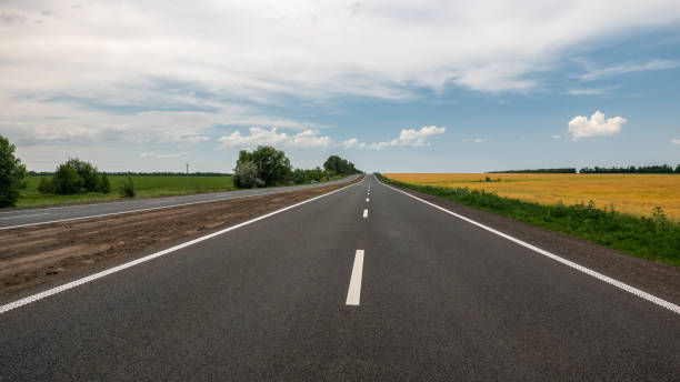 istock The motorway with white markings running along the field with wheat. 981398514