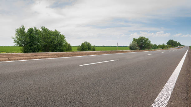 istock The motorway with white markings running along the field with wheat. 981398518