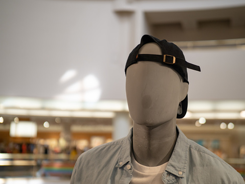 A male mannequin with backwards baseball cap in a department store