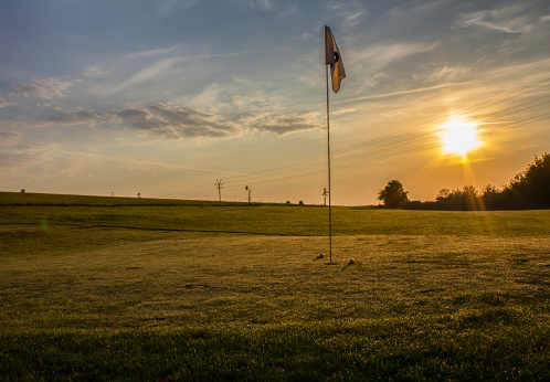 Golf course with two balls near flag in sunrise