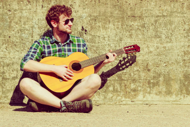 istock Young bearded hipster man with guitar outdoor 981406236