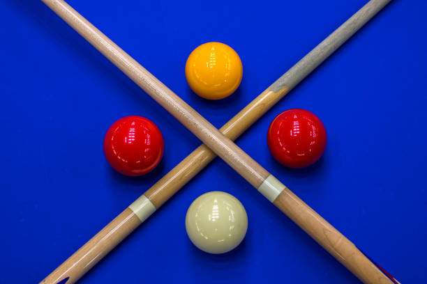 Balls with a cue lie on the green cloth of a billiard table, background.