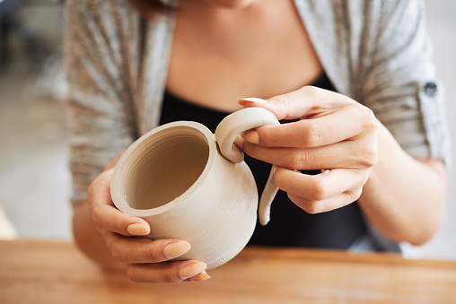 Close-up image of woman attaching handle to the mug she made