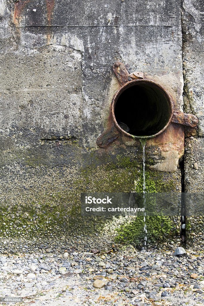 Tubo de descarga de desecho en pared de cemento; daños medioambientales - Foto de stock de Agrietado libre de derechos