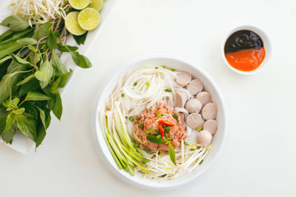Woman eating traditional Vietnamese Pho noodle using chopsticks.