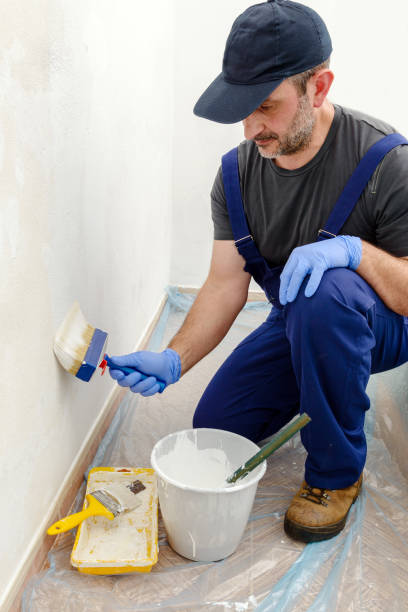 istock Painter paints the wall with the tint of white. 981477254