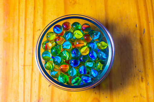 Colored marbles on wooden background