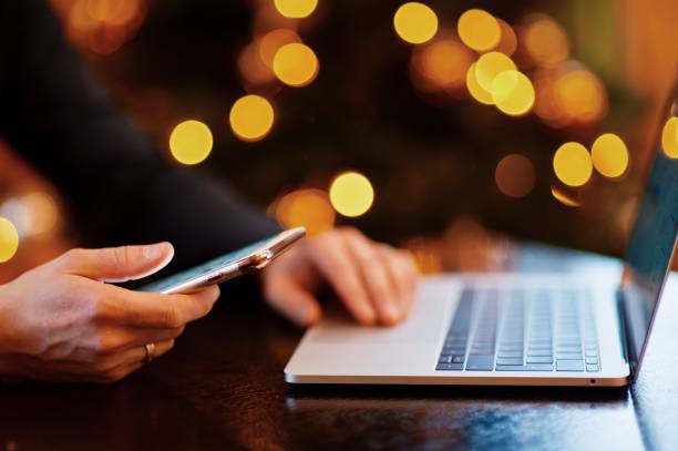 istock Cropped Hands Of Man Using Smart Phone By Laptop At Table 981477848